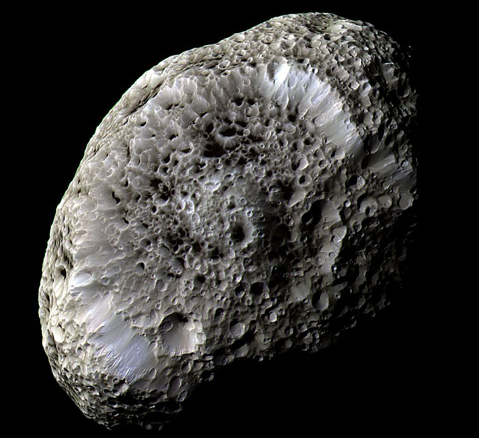 Der Mond Hyperion, der hier bildfüllend dargestellt ist, wirkt wie ein Schwamm. Viele Krater sind tief in seine Oberfläche eingegraben. Die Farben im Bild zeigen vermutlich unterschiedliche Zusammensetzungen.