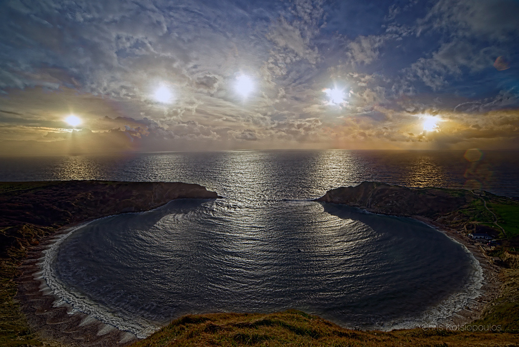 Die Wellen bei der Lulworth Cove bilden ein auffälliges Interferenzmuster, das bei Sonnenuntergang gut erkennbar ist. Die Sonne folgt auf 5 Bildern dem tiefsten Tagesbogen des Jahres zur Sonnenwende.