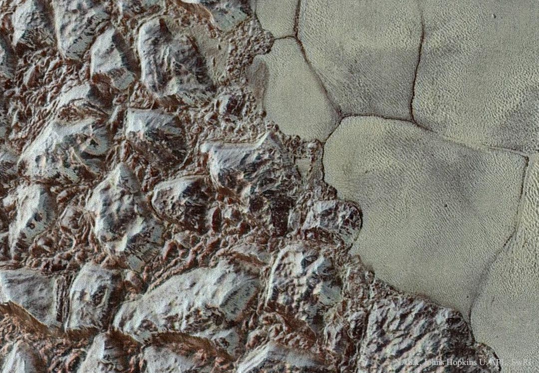 Links unten ragen zerklüftete Berge von Plutos Oberfläche auf. Scharf abgegrenzt beginnt rechts oben glattes Gelände, das durch Gräben aufgeteilt ist. Es ist von Eisgruben übersät. Das glatte Gelände gehört zur herzförmigen Ebene Sputnik Planitia.