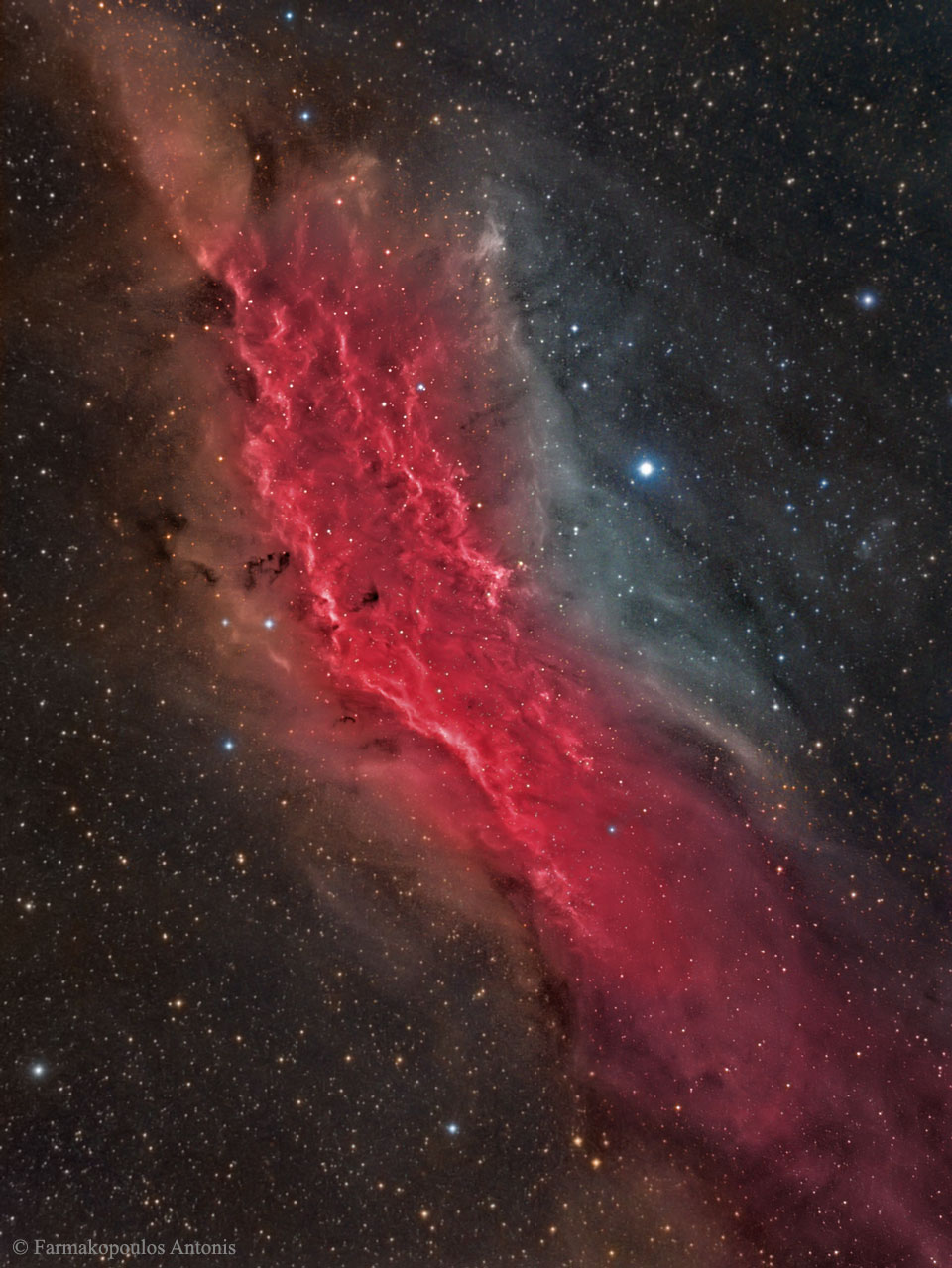 Ein rot leuchtendes Staubband zieht sich diagonal durchs Bild. Es ist in viele kleine Sterne eingebettet.