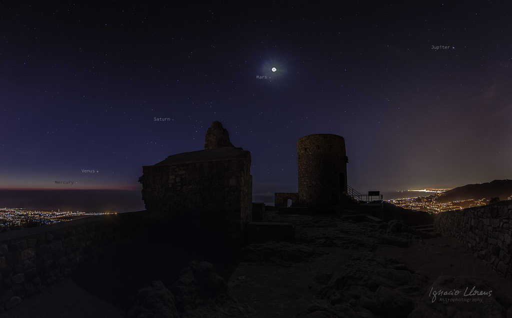 Über der Ruine von Castell de Burriac sind Mond und Planeten am dunklen Himmel in der Dämmerung verteilt.