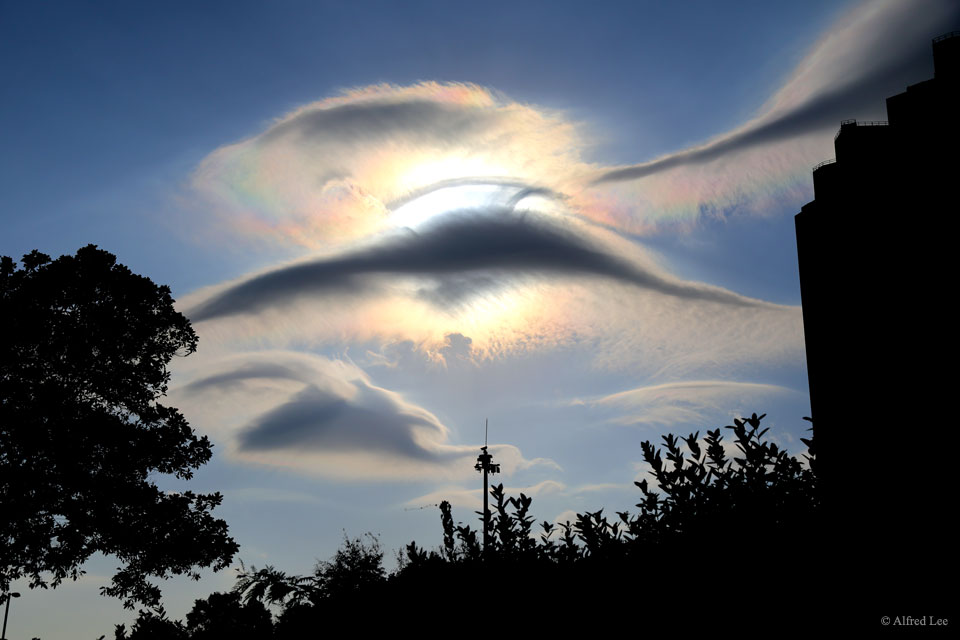 Hinter Lenticularis-Wolken schillert eine irisierende Wolke. Das Bild entstand in der Nähe von Hongkong, beide Wolkenarten sind dort sehr selten.