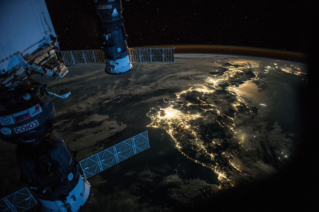 Der Astronaut Scott Kelly zeigt uns Japan aus der Perspektive der Internationalen Raumstation ISS. Links sind zwei Raumkapseln angedockt, eine Sojus und eine Progress. Hinten leuchtet über dem gekrümmten Erdrand ein zarter Streifen Nachthimmellicht.