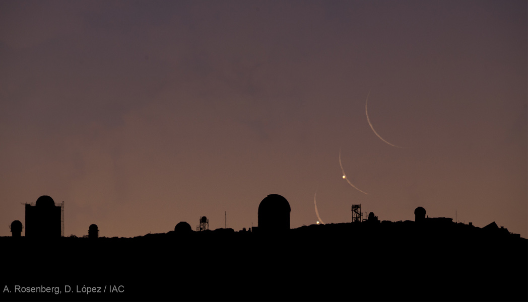 Hinter den Silhouetten der Teleskope auf der Kanarischen Insel Teneriffa gehen Mond und Venus auf. Die schmale Mondsichel bedeckt dabei den Morgenstern. Von der schmalen Mondsichel sind drei Bilder zu sehen, von der Venus nur zwei.