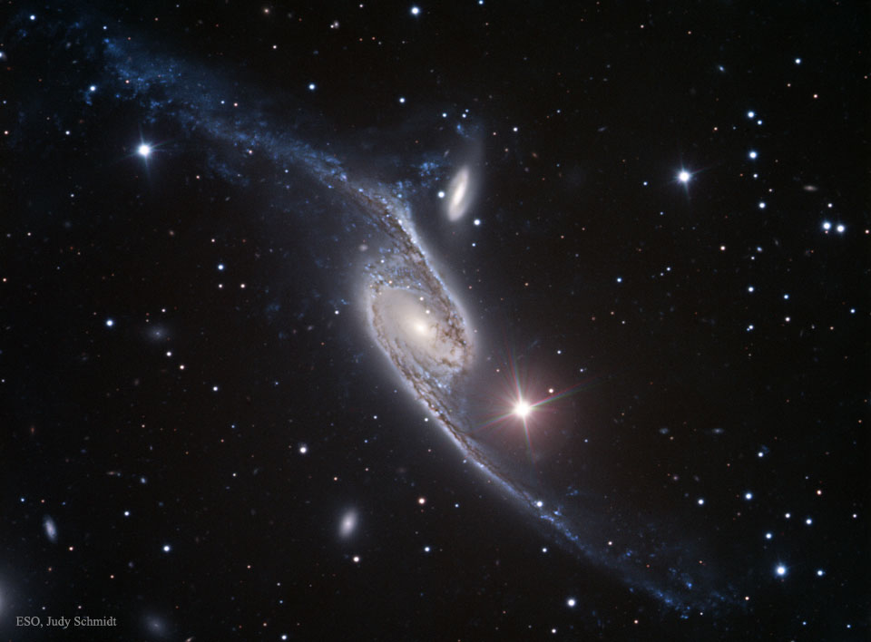 Mitten im Bild ist die lang gezogene Balkenspiralgalaxie NGC 6872 im Sternbild Pfau. Sie kollidiert mit der kleineren Galaxie GC 4970. Wahrscheinlich entstanden die ausladenden Arme durch Gezeitenkräfte.