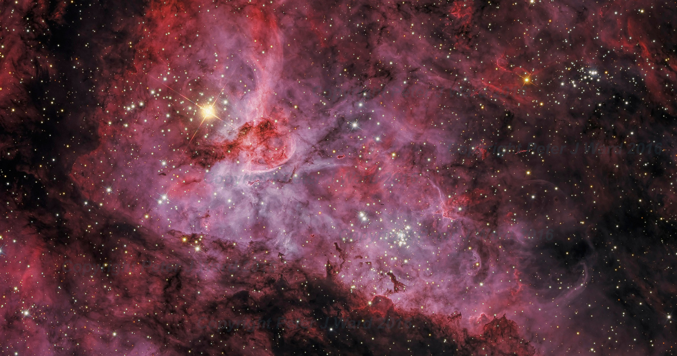 Der Carinanebel im Bild leuchtet rötlich und besteht aus lebhaften Fasern aus Gaswolken. Links oben leuchtet der helle Stern Eta Carinae. Im Bild sind Sternhaufen verteilt.