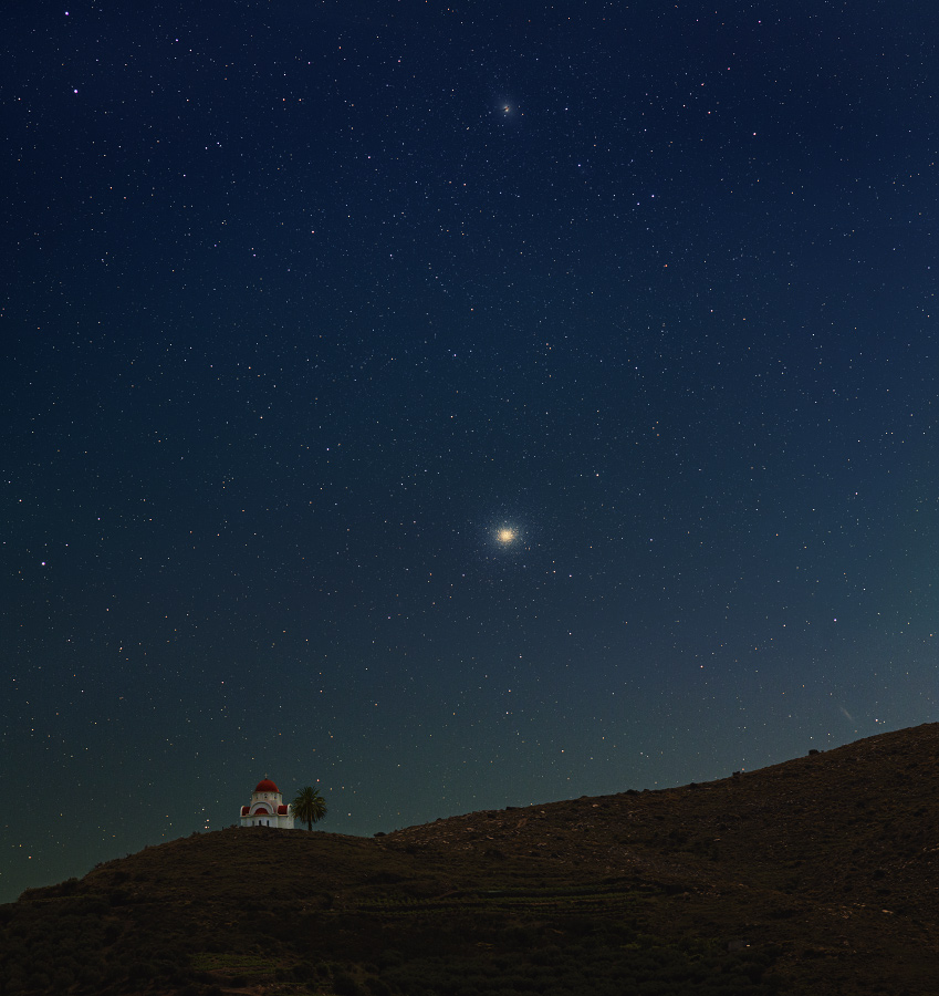 Die nächtliche Szenerie zeigt eine Kirche auf einem Hügel auf Kreta. Am Himmel leuchtet etwa in der Mitte der Kugelsternhaufen Omega Centauri, oben ist die aktive Galaxie Centaurus A.