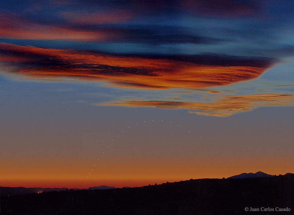 Im Abendrot zieht Merkur eine Schleife. Die Bilder wurden jeden Abend fotografiert, wenn die Sonne 10 Grad unter dem Horizont stand. Oben sind Wolken von unten rot beleuchtet.