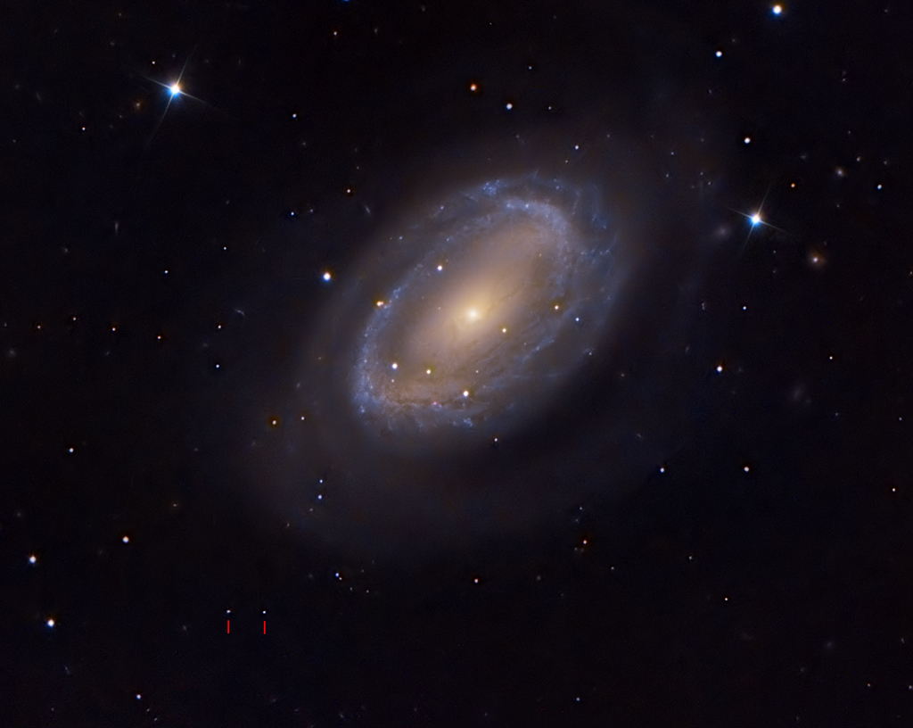 Über der Mitte leuchtet eine Spiralgalaxie mit nur einem Arm im Sternbild Haar der Berenike. Links unten sind zwei Lichtpünktchen mit roten Strichen markiert. Es ist der Zwergplanet Makemake im Kuipergürtel.