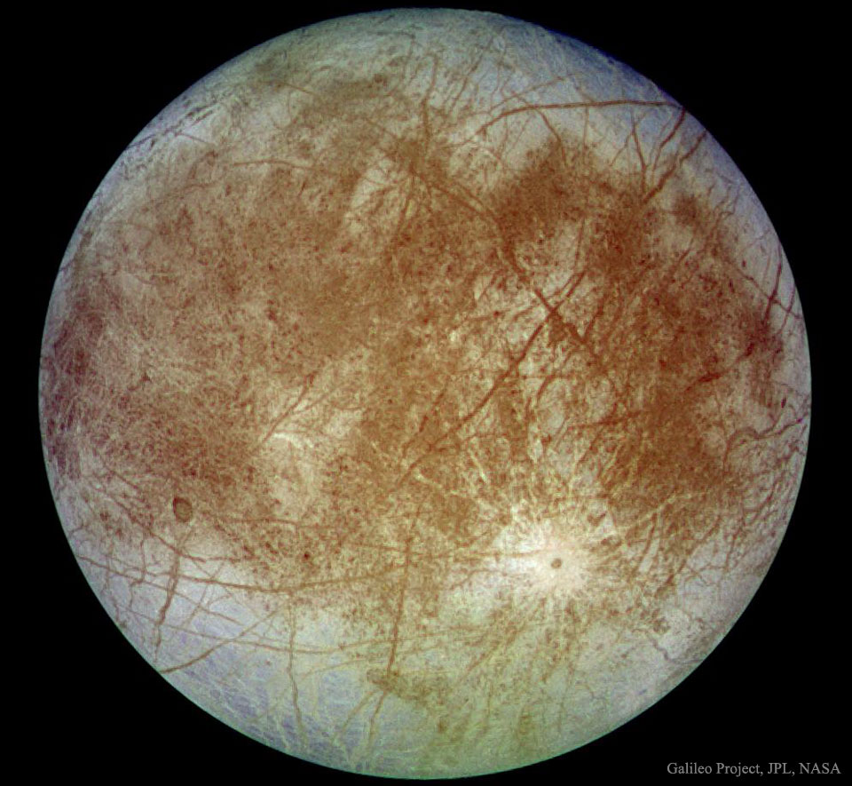 Der Jupitermond Europa wirkt hier wie eine verdreckte Kristallkugel. Er ist von vielen rötlichen Brüchen überzogen. Auf der Oberfläche breiten sich riesige rötliche Flecken aus. Am Rand wirkt er fast durchsichtig.