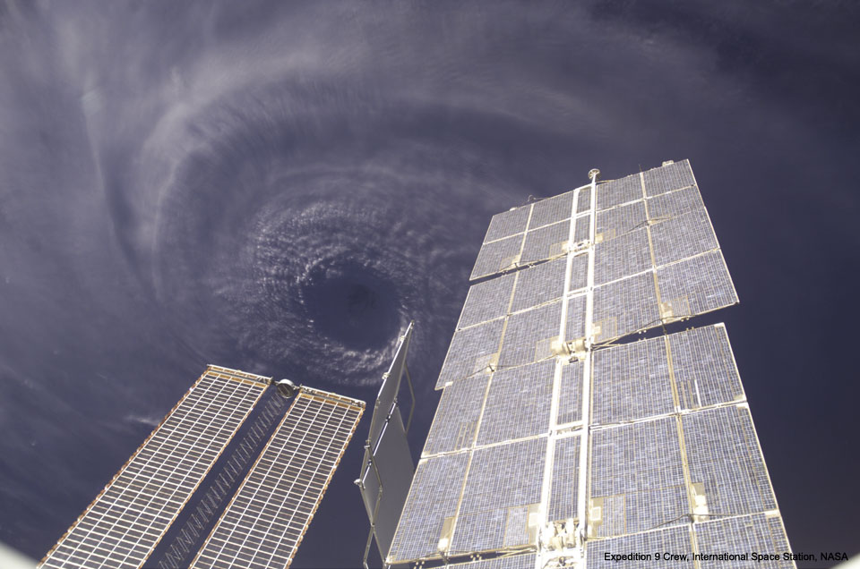 Unter den Solarpaneelen und Gitterelementen der Internationalen Raumstation braut sich das Auge des Wirbelsturms Ivan zusammen.