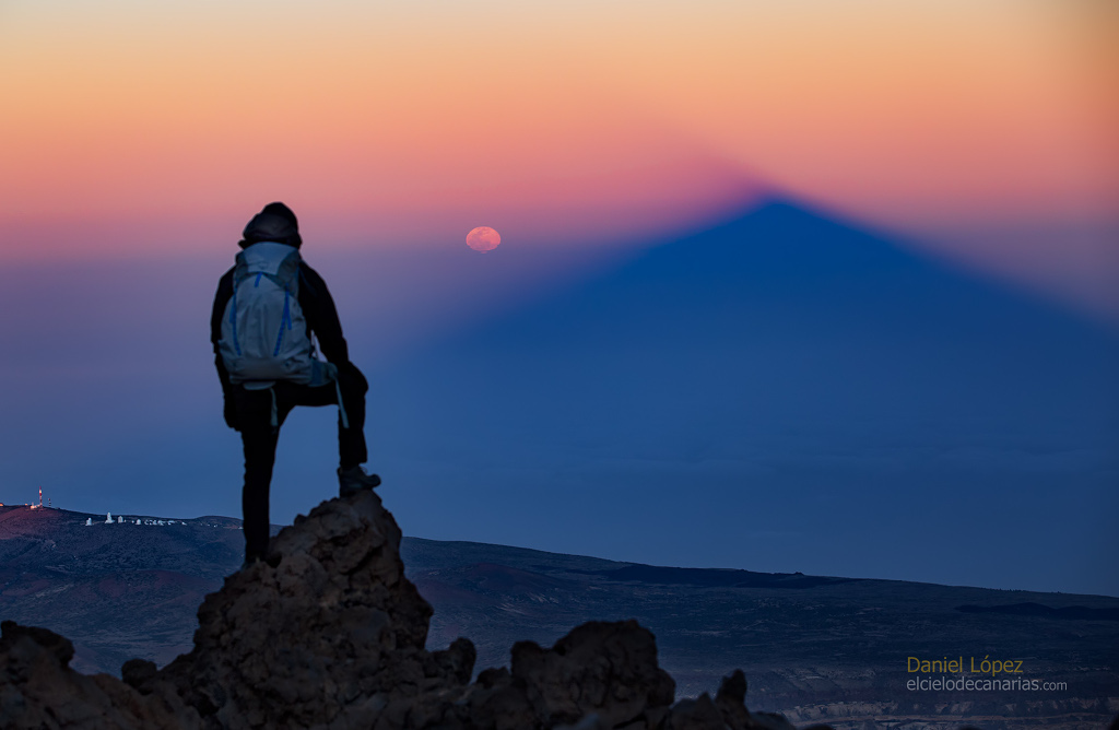 Am Himmel wirft ein hoher Berg seinen Schatten in die Abenddämmerung, der Schattenkegel ist blaugrau, darüber ist ein helles Abendrot. Links neben dem Schatten geht der Mond auf, er ist rötlich und verzerrt. Vorne steht eine Person mit dem Rücken zu uns, sie blickt von einem Berg hinab und steht auf einem Felsen, der rechte Fuß aufgestellt, die rechte Hand liegt auf dem Knie.